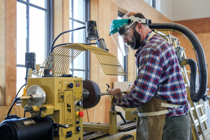 A man using the lathe in the Makerspace woodshop